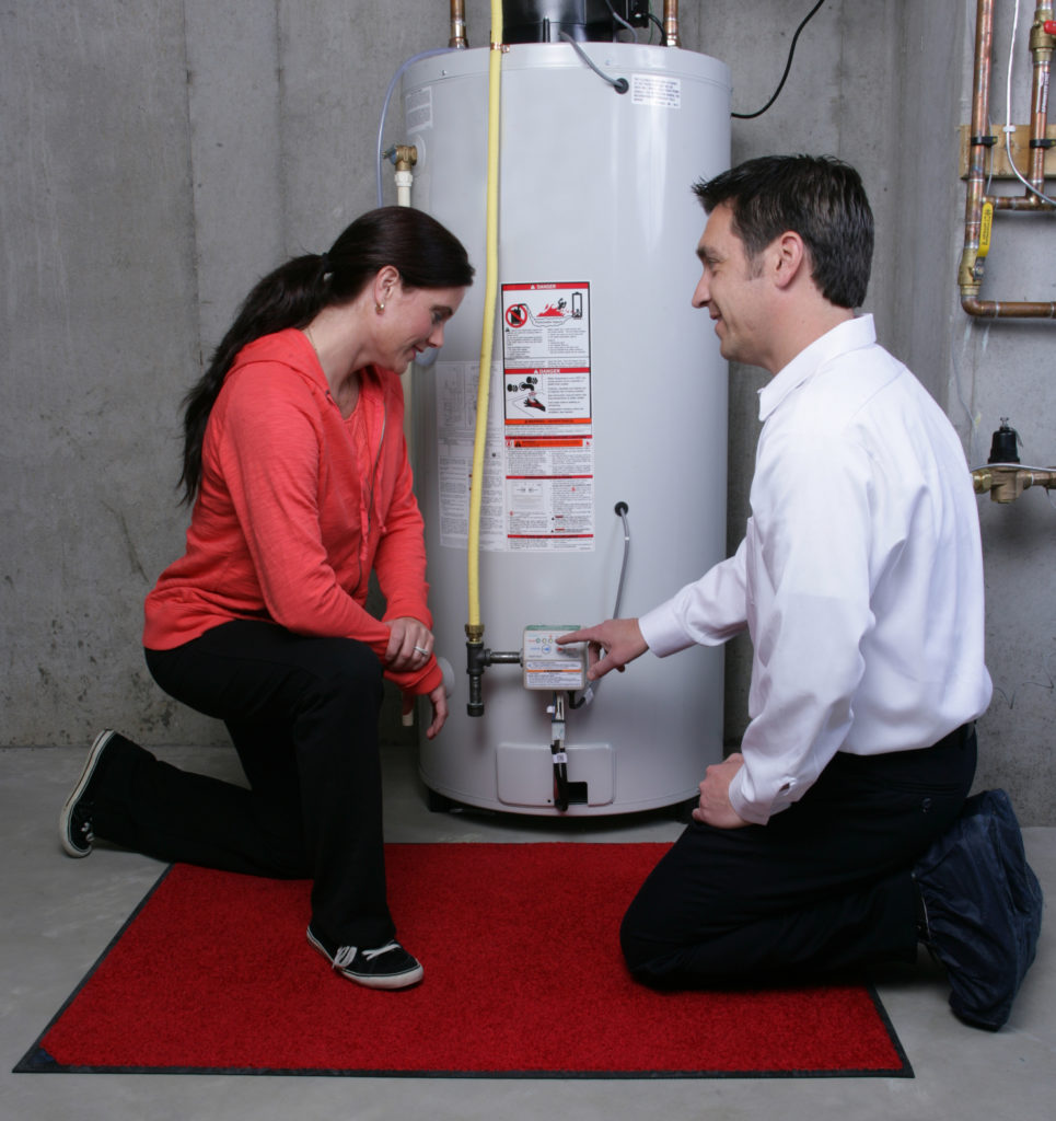 Plumber showing a female homeowner how to operate her newly installed water heater unit