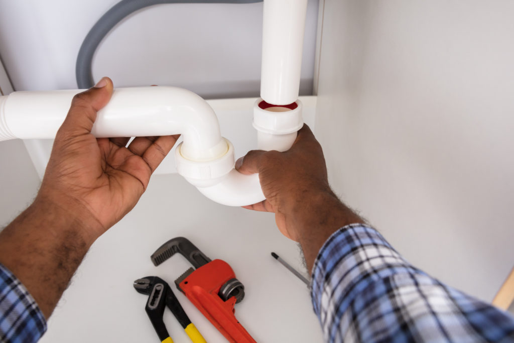 Plumber clearing a clogged kitchen sink drain